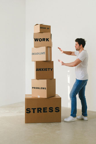 Homme avec des boîtes WORK, ANXIETY, STRESS symbolisant le stress — pour l’article Devenir une personne vraie