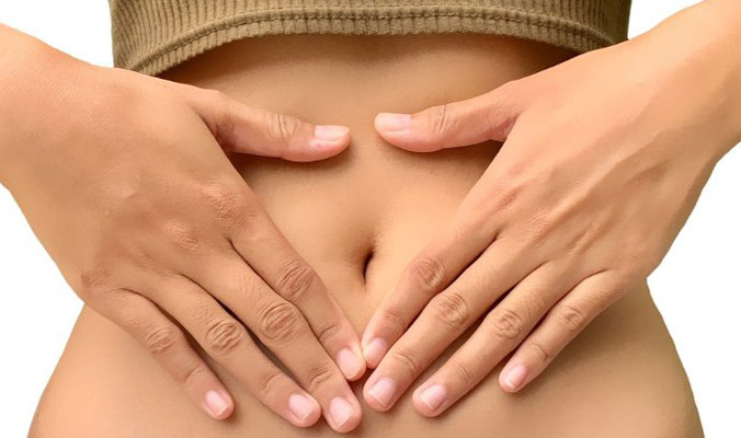 Photo du ventre nu d'une femme avec ses deux mains en triangle