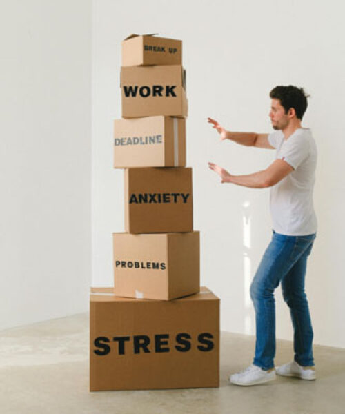 Homme avec des boîtes WORK, ANXIETY, STRESS symbolisant le stress — pour l’article Devenir une personne vraie
