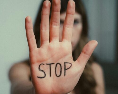 Femme tendant la main sur laquelle est il écrit STOP