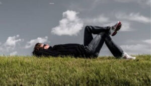 Personne allongée sur l’herbe, yeux fermés — moment de détente en extérieur
