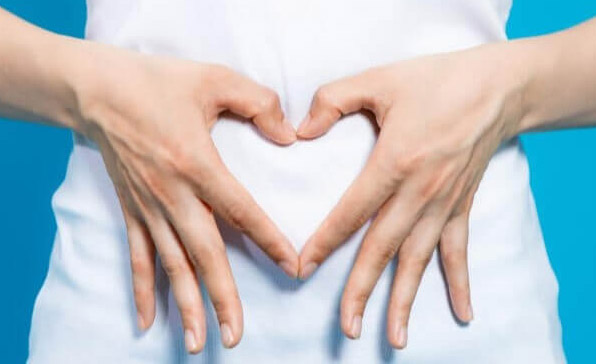 Femme habillée en plan gros plan sur son ventre et mains en cœur