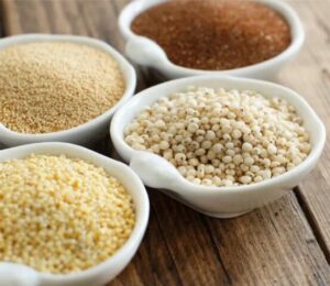 4 petits bols avec orge, millet, quinoa sur table en bois